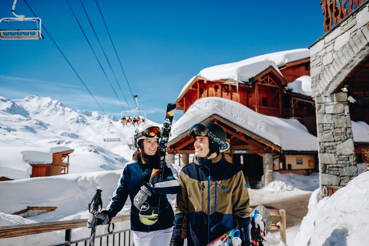 A couple walking in ski gear against the backdrop of Val Thorens ski resort